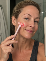 ReWired Glow Wand customer review - woman holding wand on cheek, casual home photo